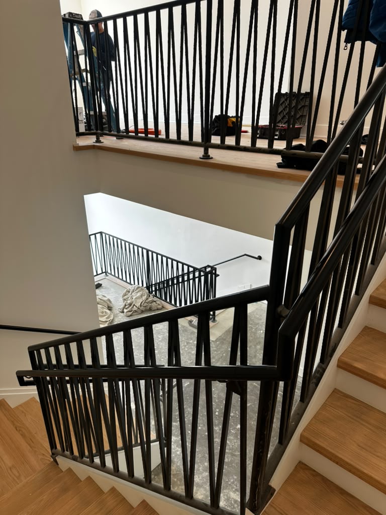 Black interior stairwell railing with decorative vertical bars across an open multi-level stair