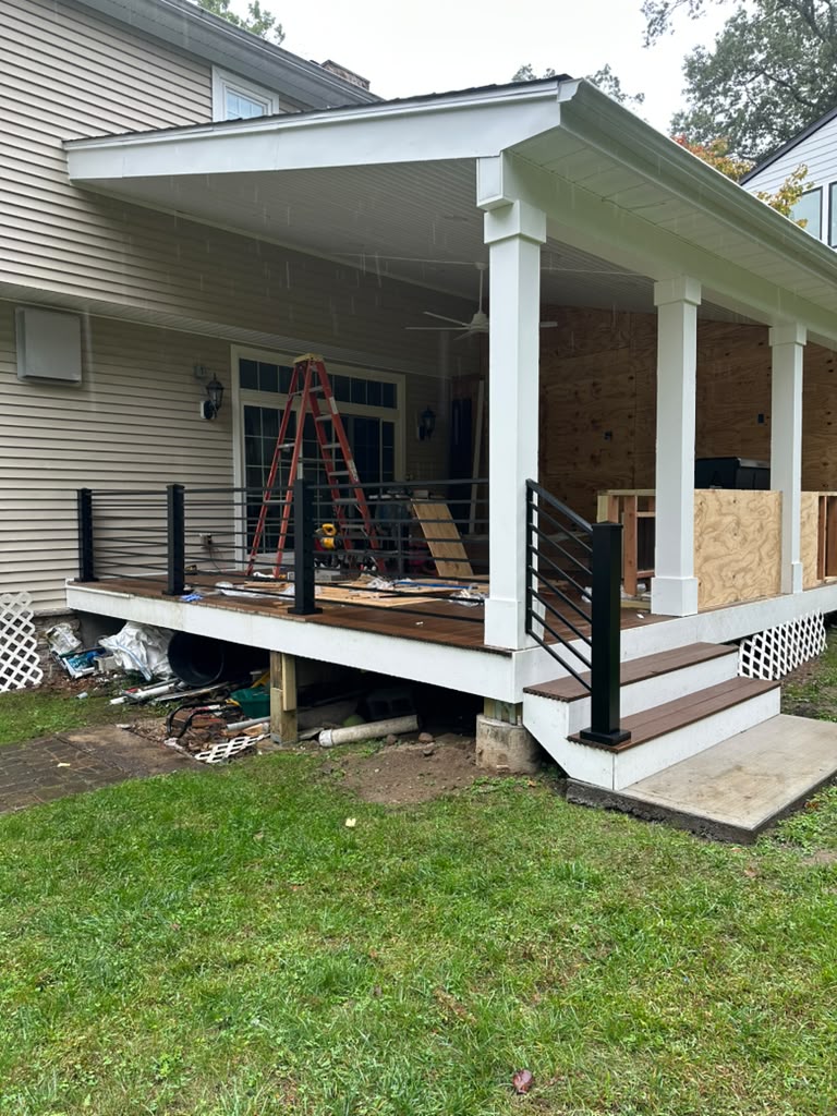 Black horizontal rod railing on a covered rear porch with white columns and wood decking