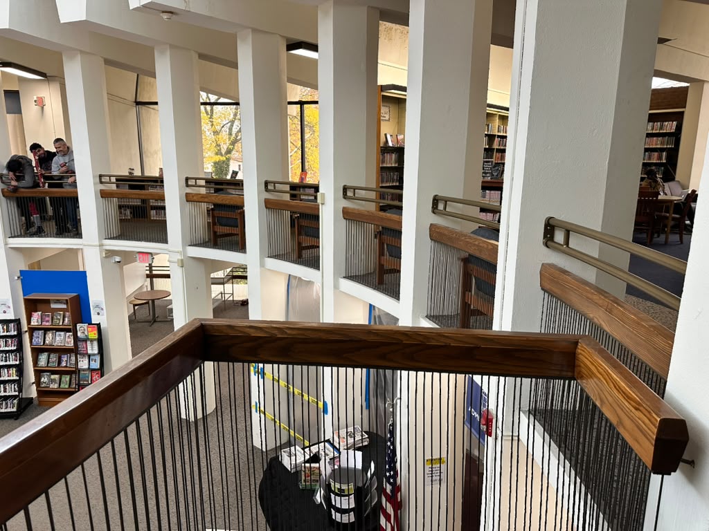 Wood-capped metal guardrail around the mezzanine of a library reading room