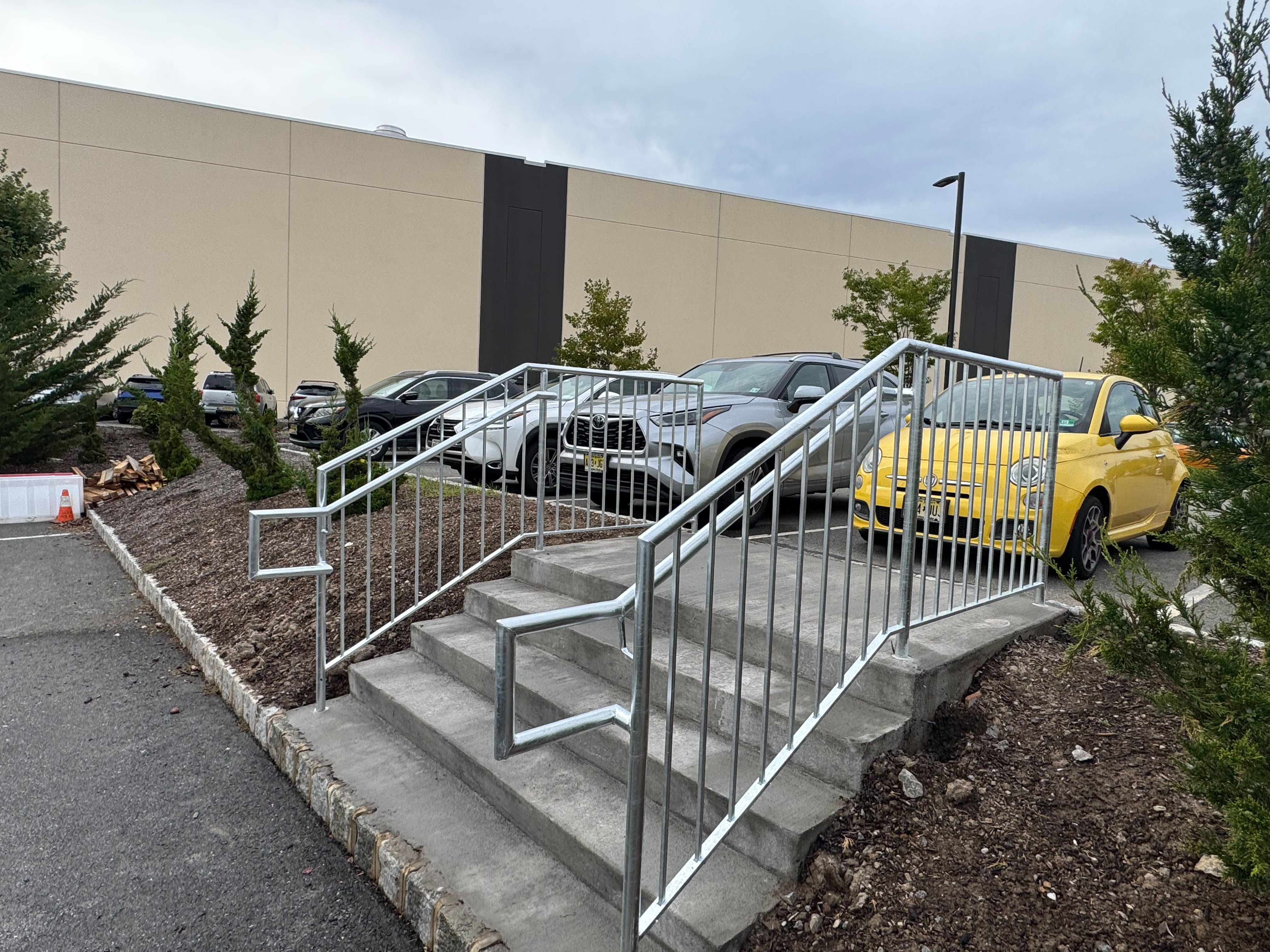 Galvanized steel handrails on the concrete entry steps of a retail building