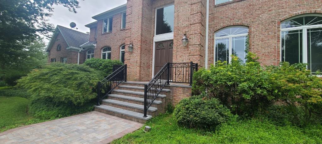 Ornamental black step railing with a scroll centre panel on the front steps of a brick colonial