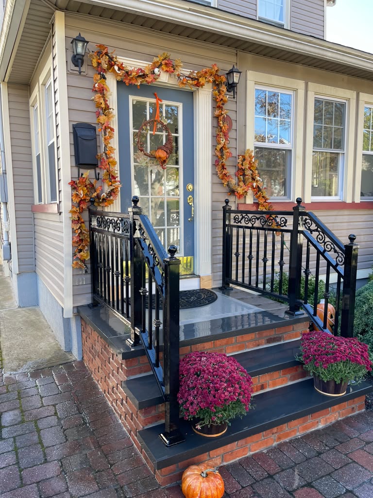 Ornamental black scroll railing on a brick entry porch with seasonal decorations