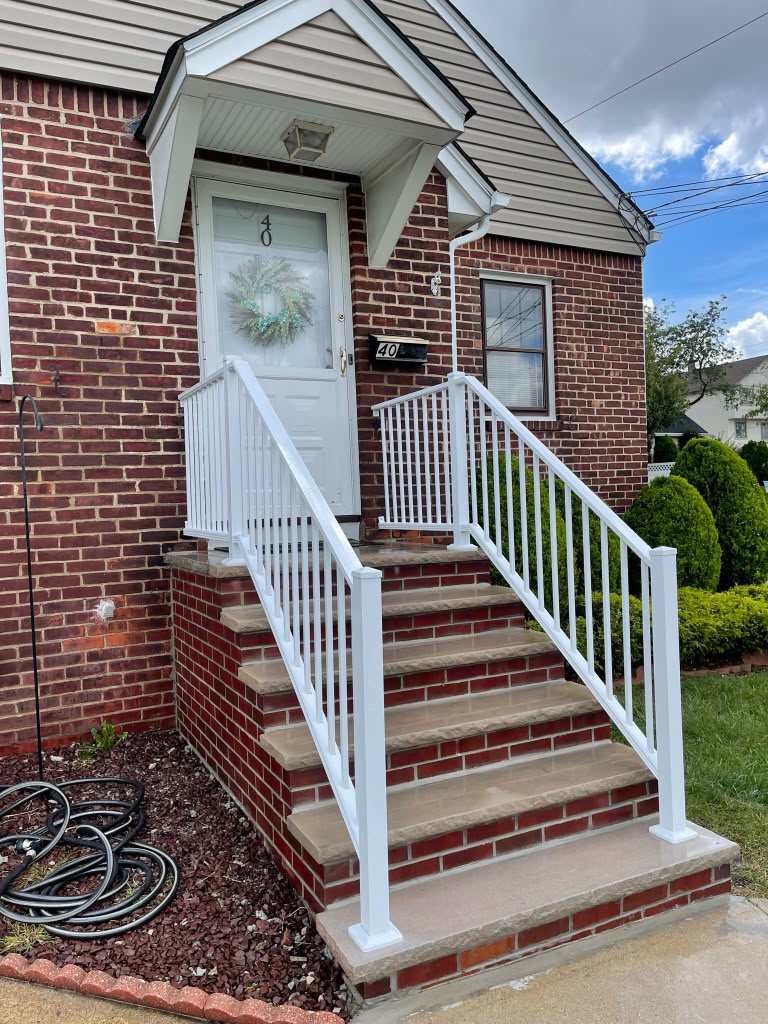 White aluminum picket railing on the brick entry steps of a red brick home