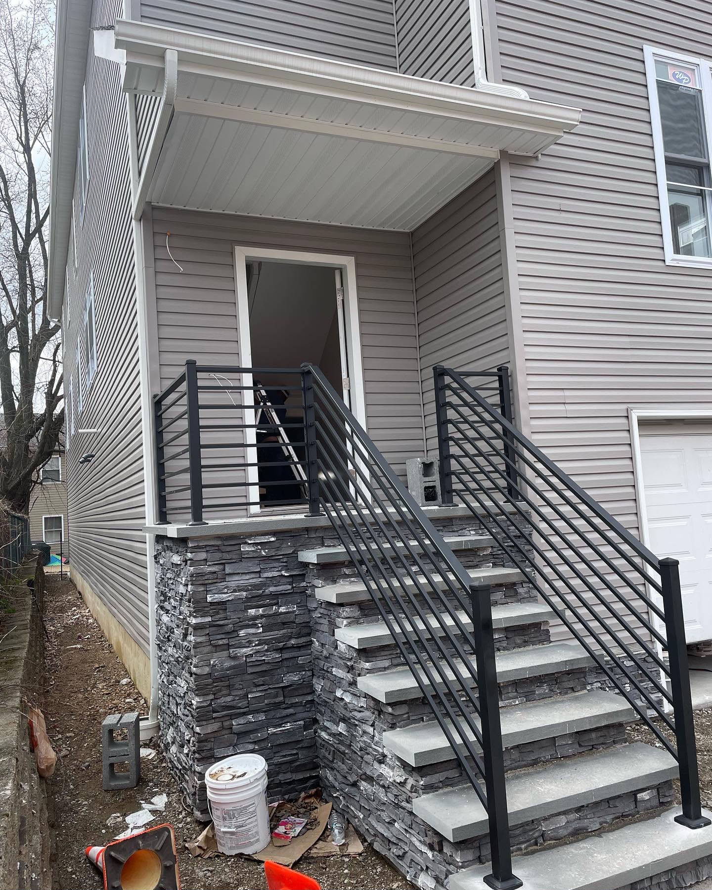 Black railing on the exterior stone stair tower of a gray-sided home