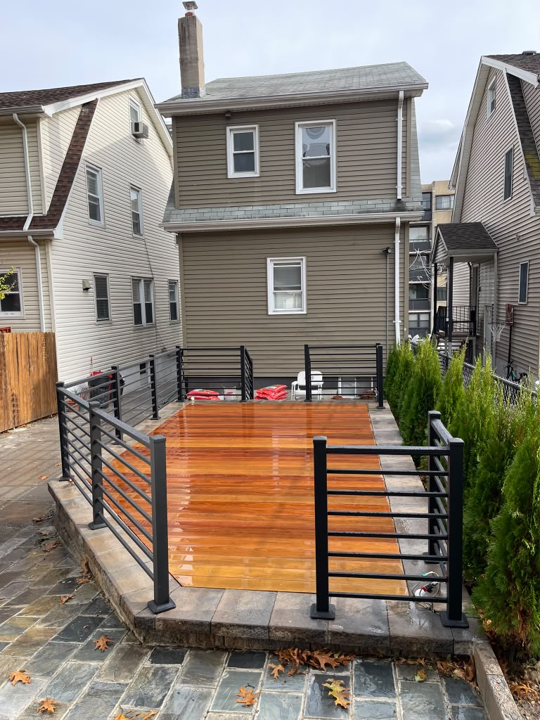 Black horizontal-rod railing around a new ipe hardwood deck on a paver patio