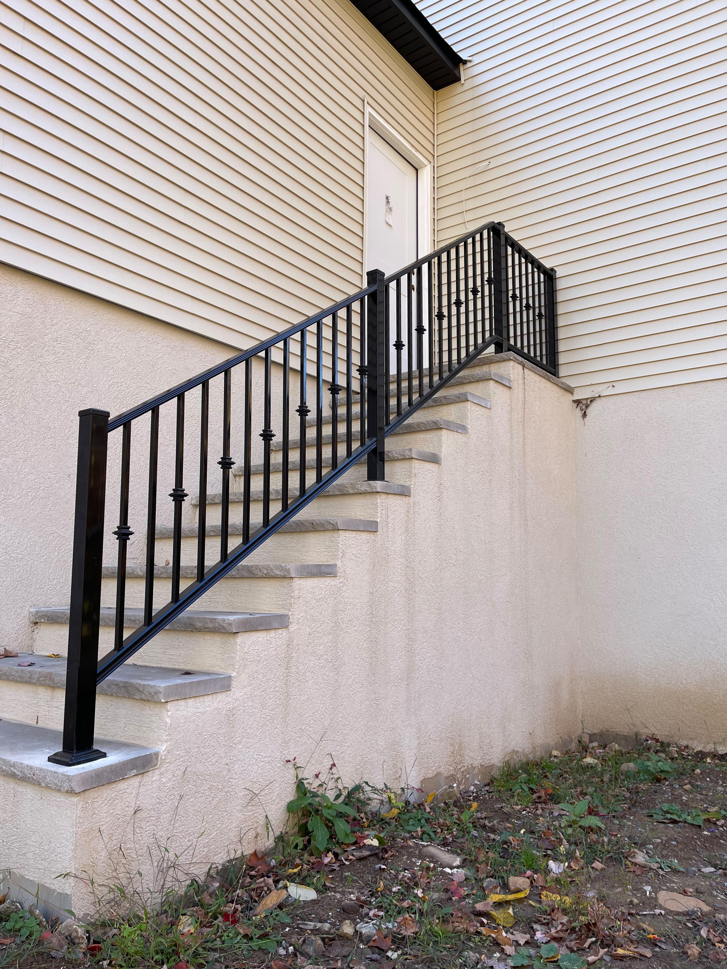 Black decorative knuckle-picket railing down a tall exterior side stair run