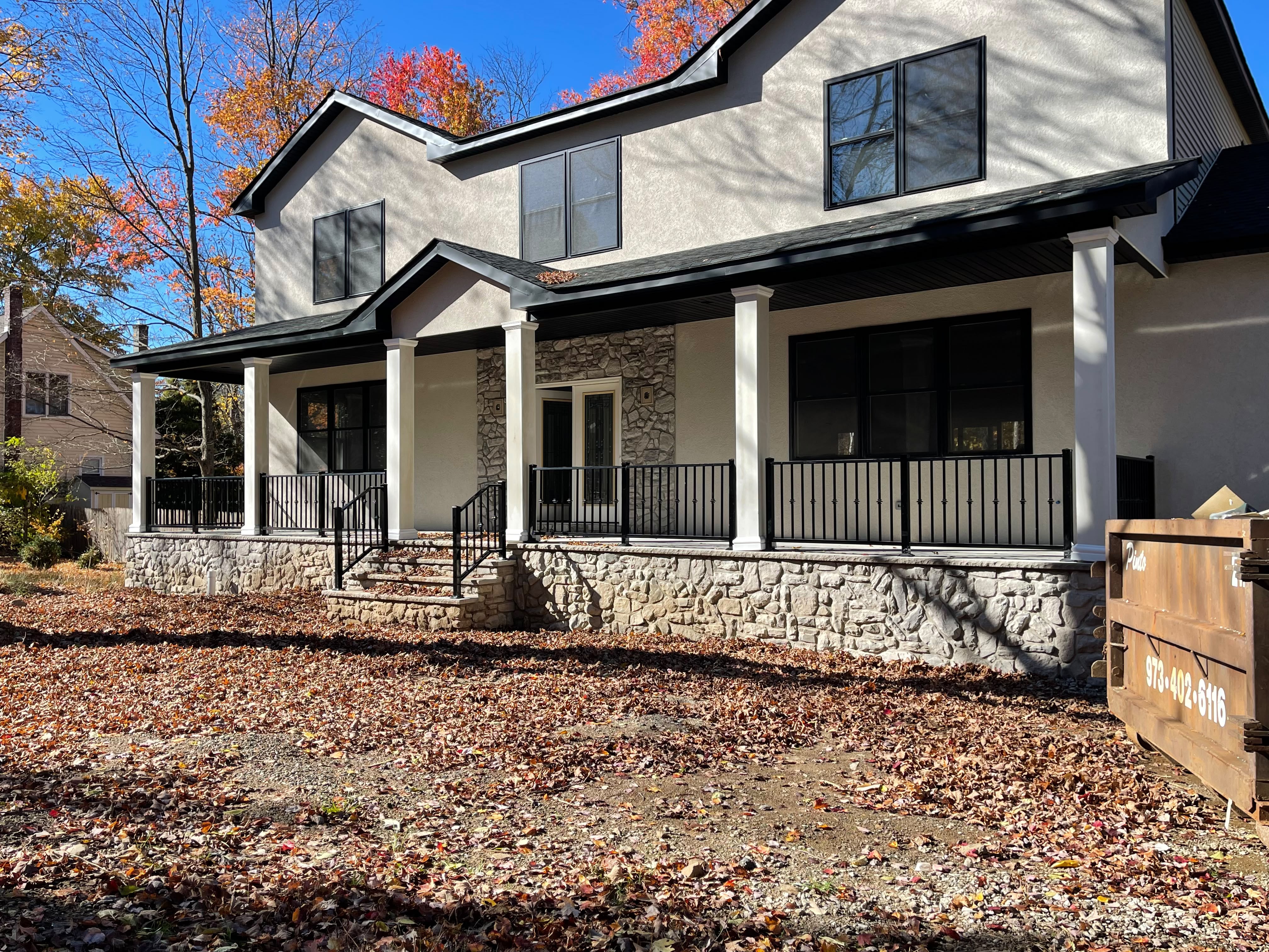 Long horizontal rod railing running the full length of a covered front porch on a new stucco home