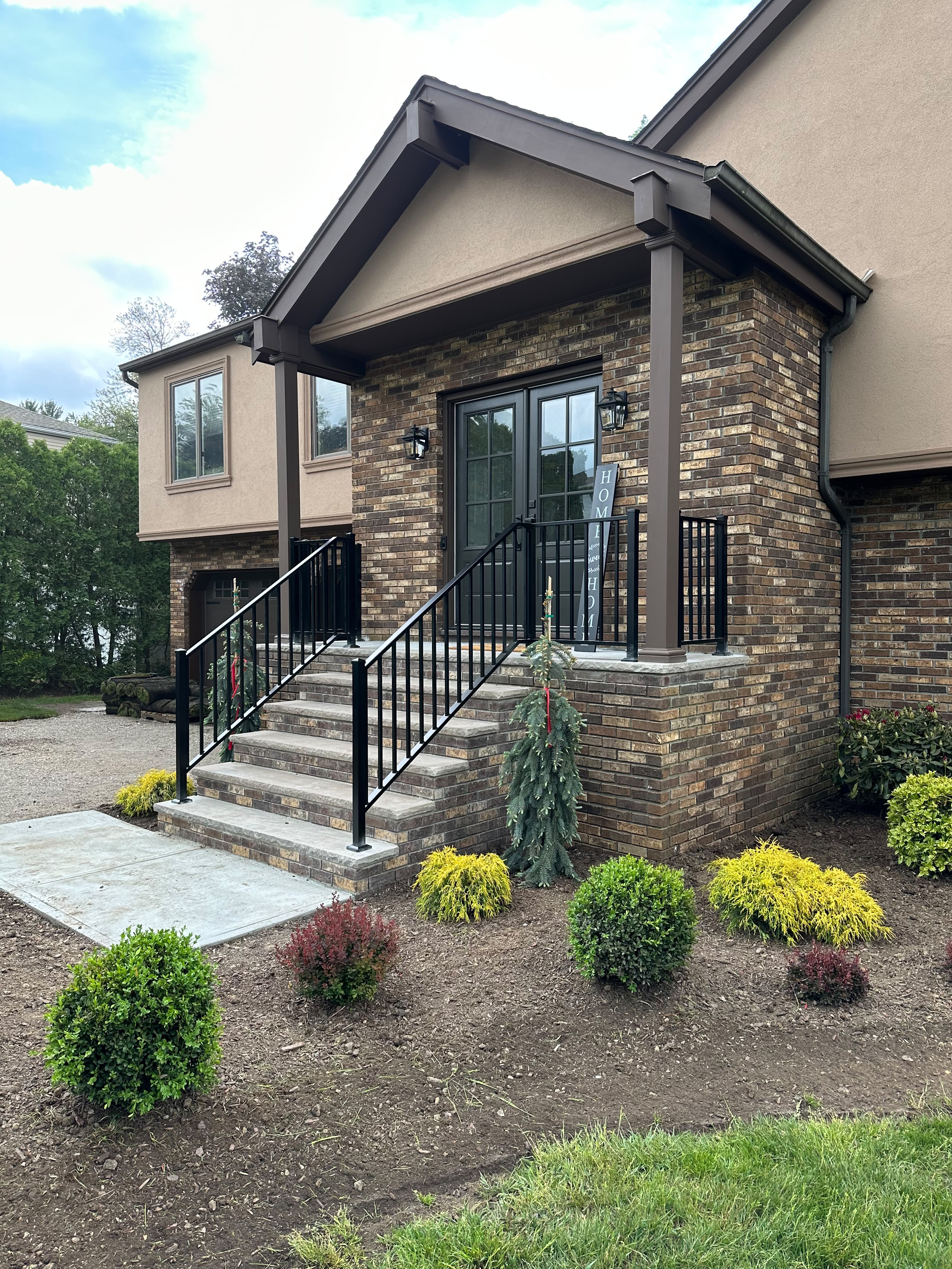 Black picket railing on the brick entry steps and porch of a stucco home