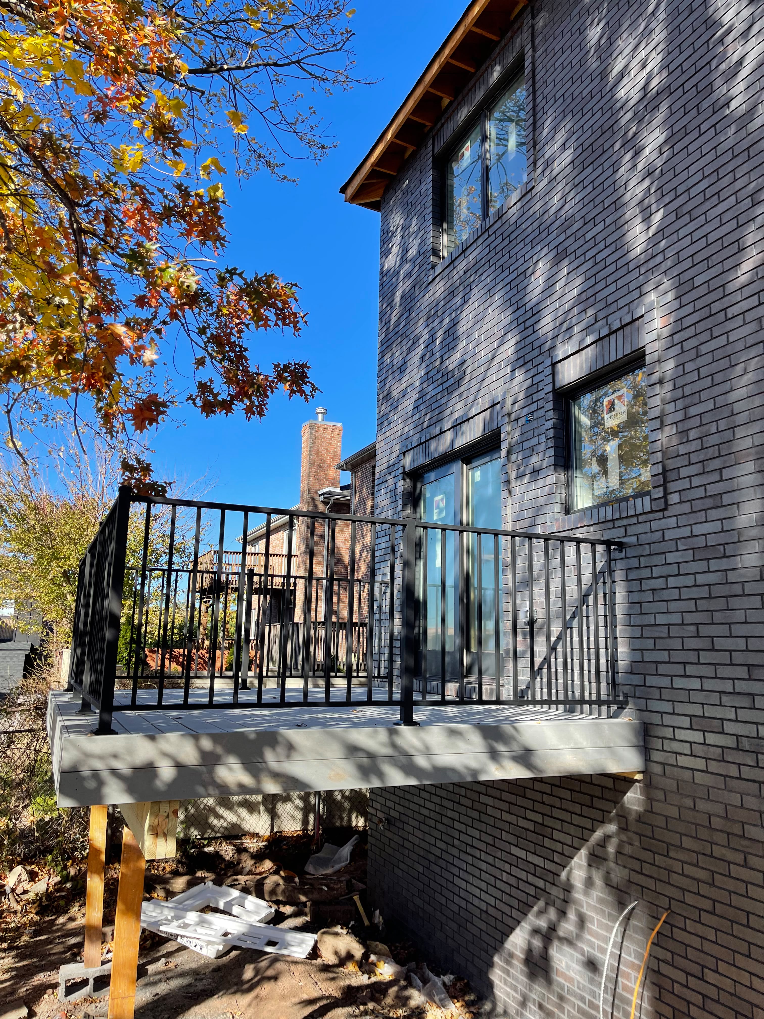 Black railing around a new concrete balcony at a charcoal brick home