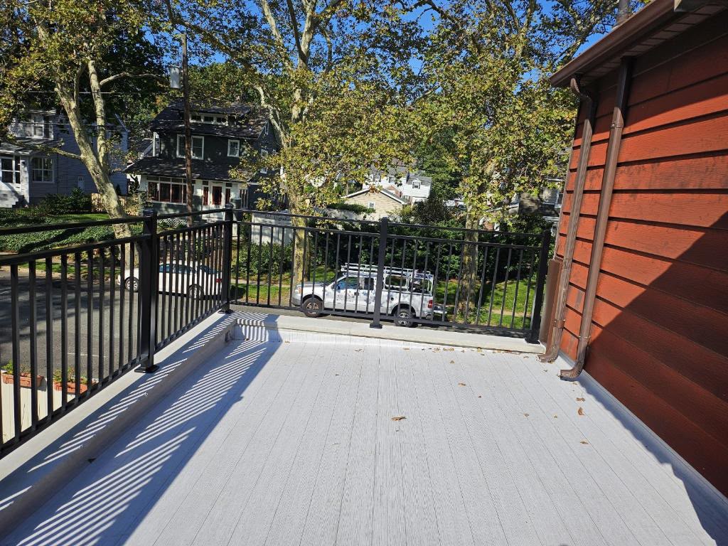Black railing around a flat roof deck built over a garage at a cedar-sided home