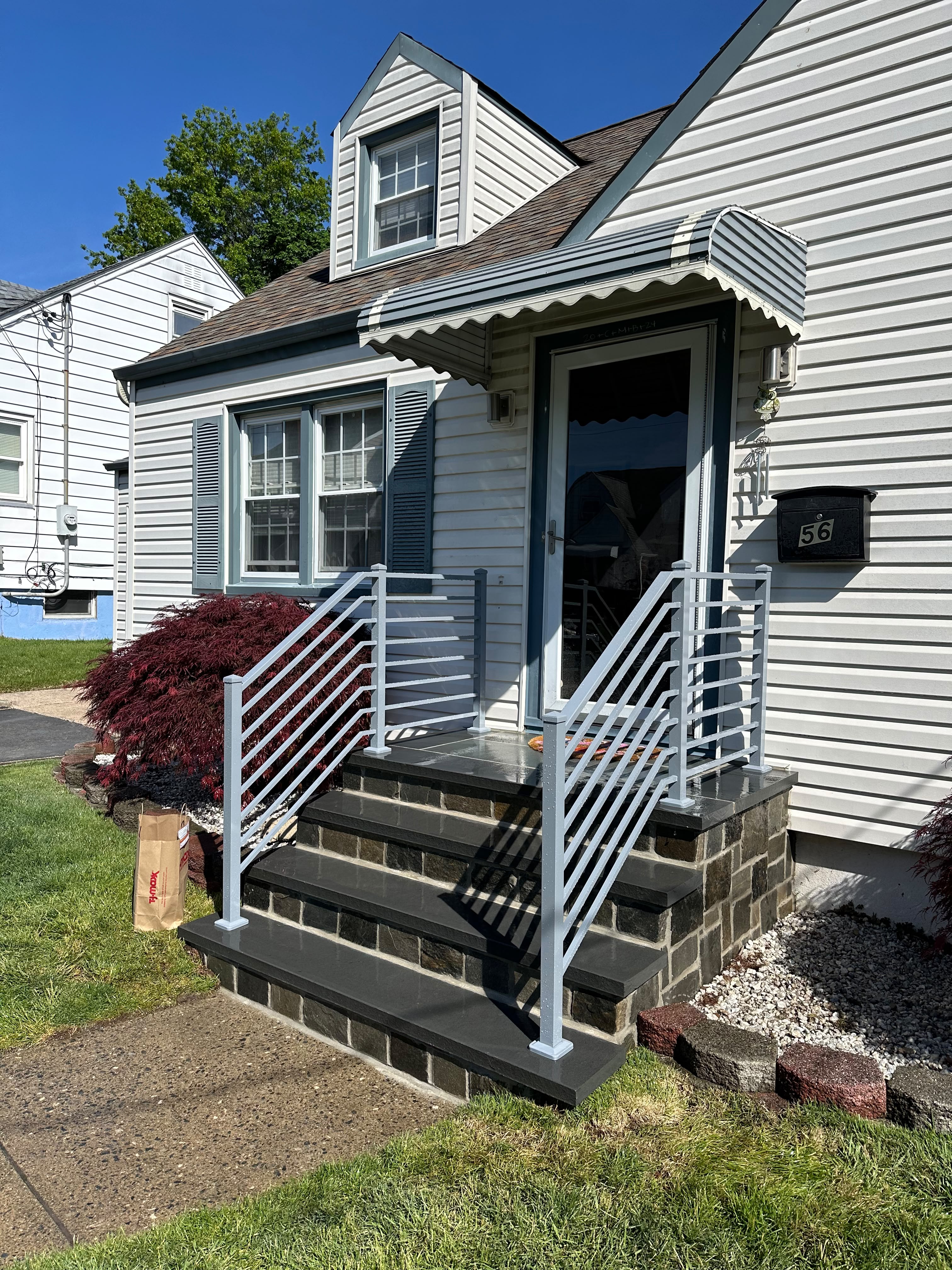 Custom silver-gray aluminum railing with a diagonal bar pattern on dark stone entry steps