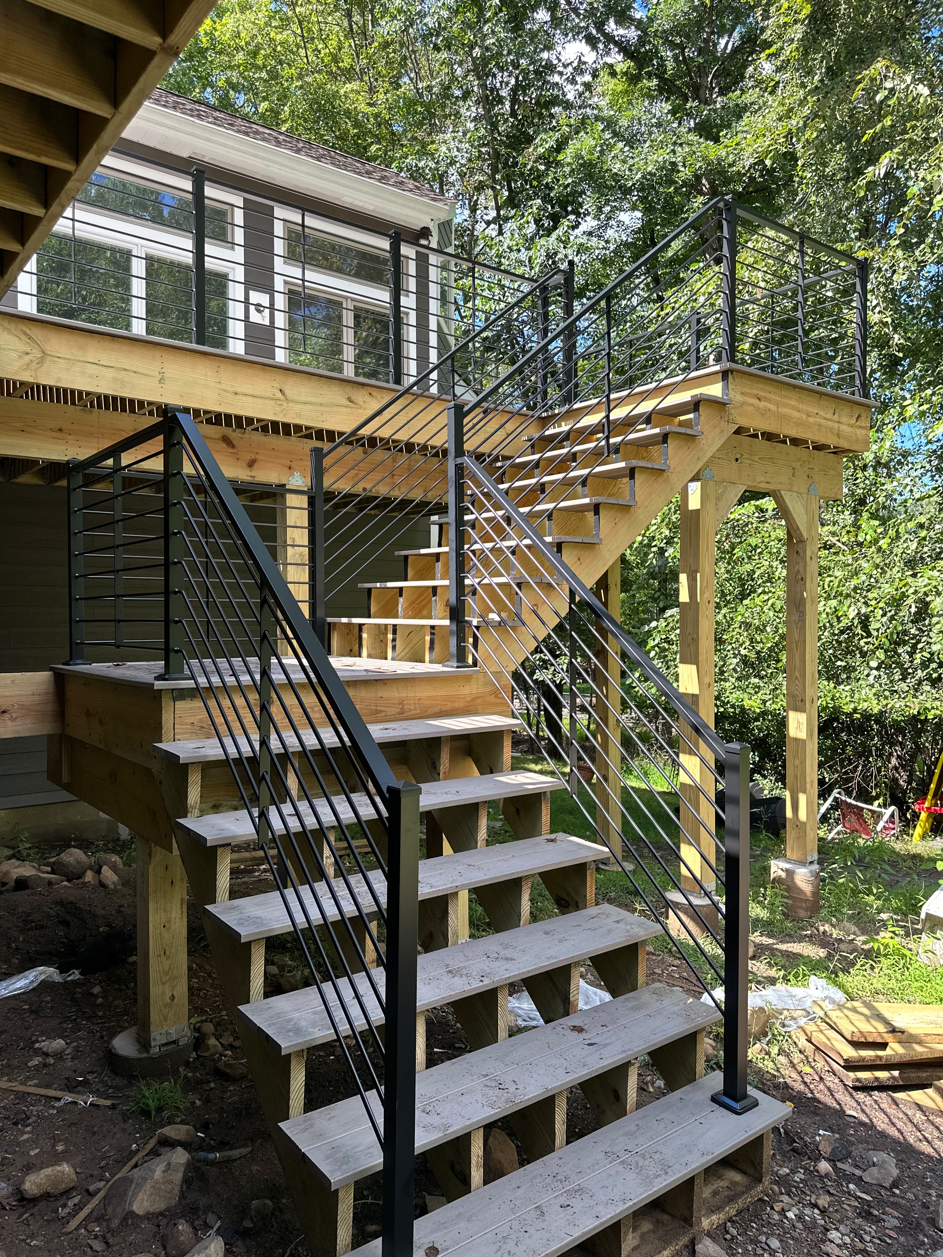 Black cable railing on the new wood deck and stairs of a dark modern home
