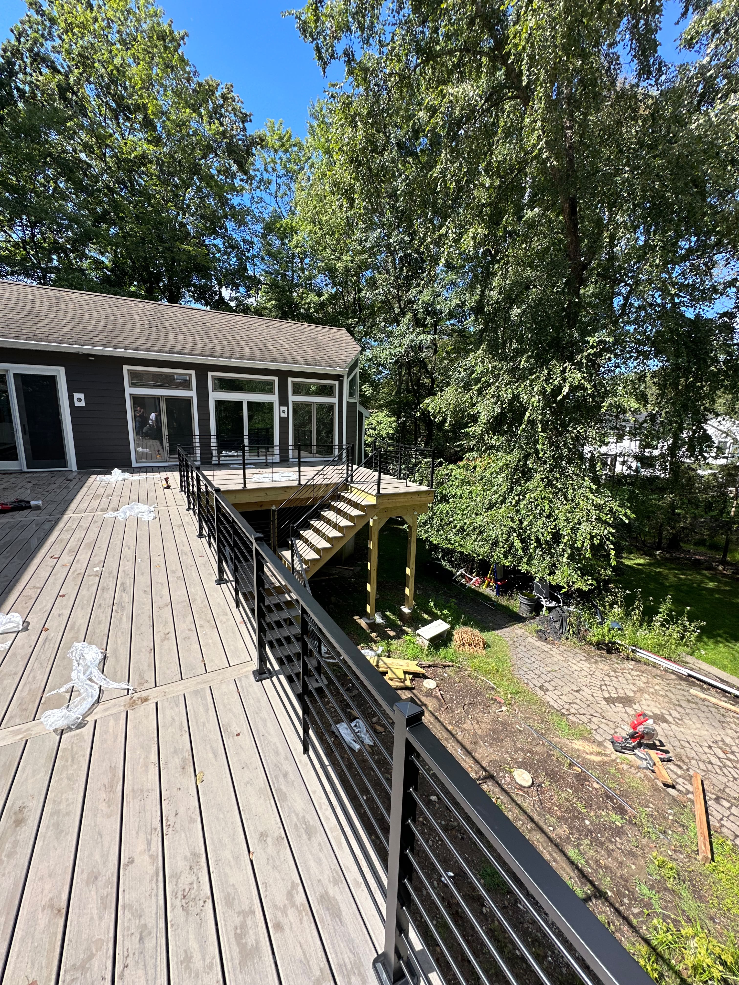 Black horizontal railing around a gray composite deck and steps at a dark-sided home
